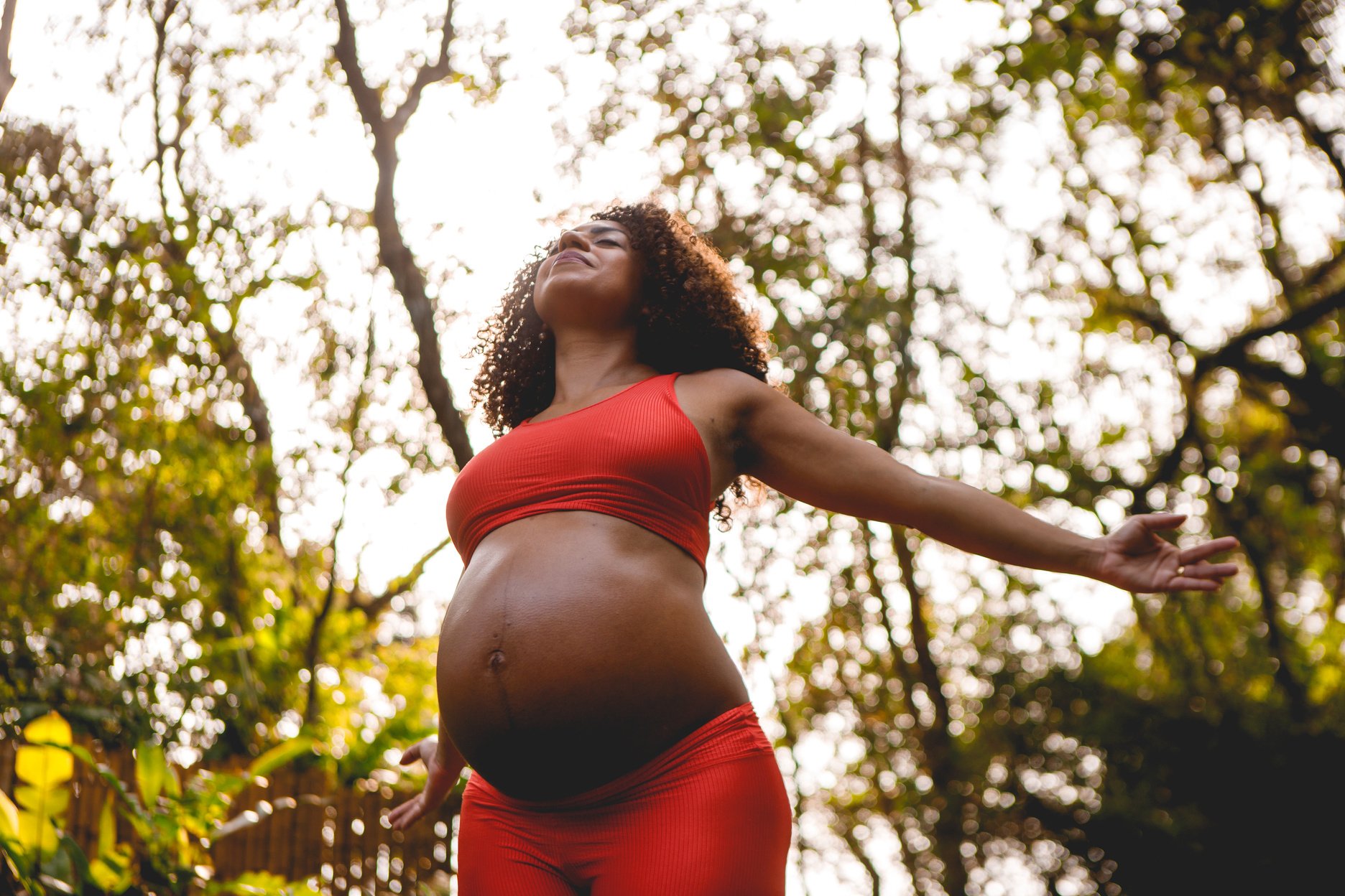 pregnant black woman doing yoga outdoors